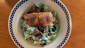 Salmon filet on top of salad bed