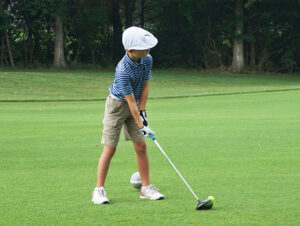 Young boy teeing off on a fairway