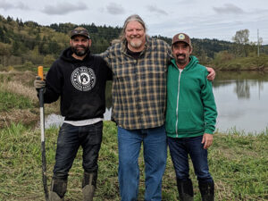 Bill Ranniger with two men working at a volunteer Duke's Seafood planting project